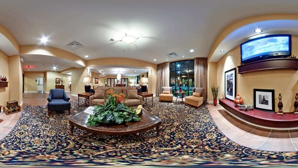 A spacious lobby with a large, ornate carpet, multiple seating areas, and a television mounted on the wall. - Hampton Inn Jackson (Jackson)