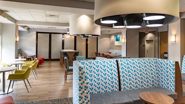 A modern hotel lobby with seating areas, tables, and a patterned sofa.