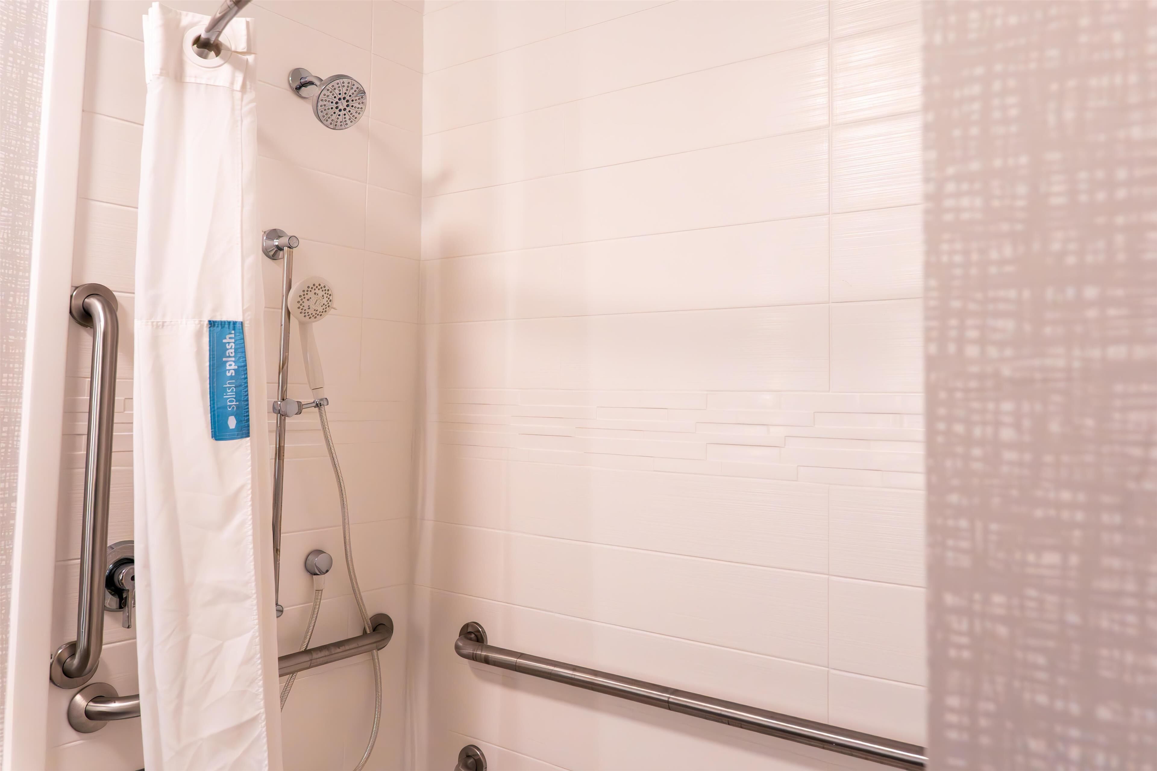 A shower area with a handheld showerhead, a wall-mounted showerhead, and a handheld shower hose.