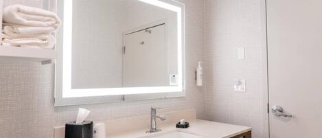 Un baño moderno con un espejo grande, un lavamanos blanco y un perchero para toallas.
