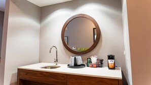 A bathroom with a sink, mirror, and coffee maker.