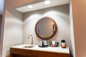 Baño con lavamanos, espejo y cafetera.