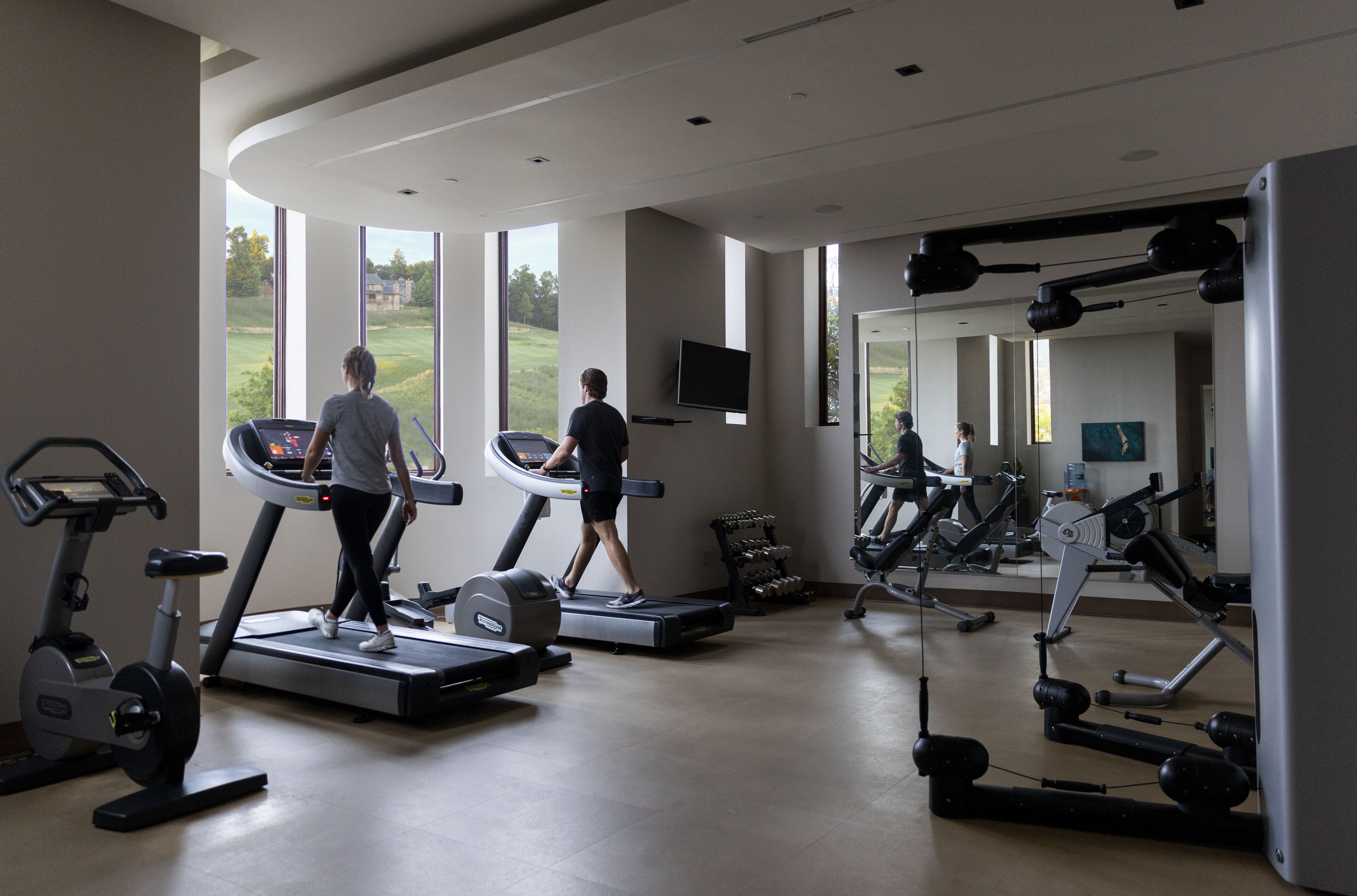 Une salle de sport équipée de tapis de course, de vélos d’appartement et d’appareils de musculation.