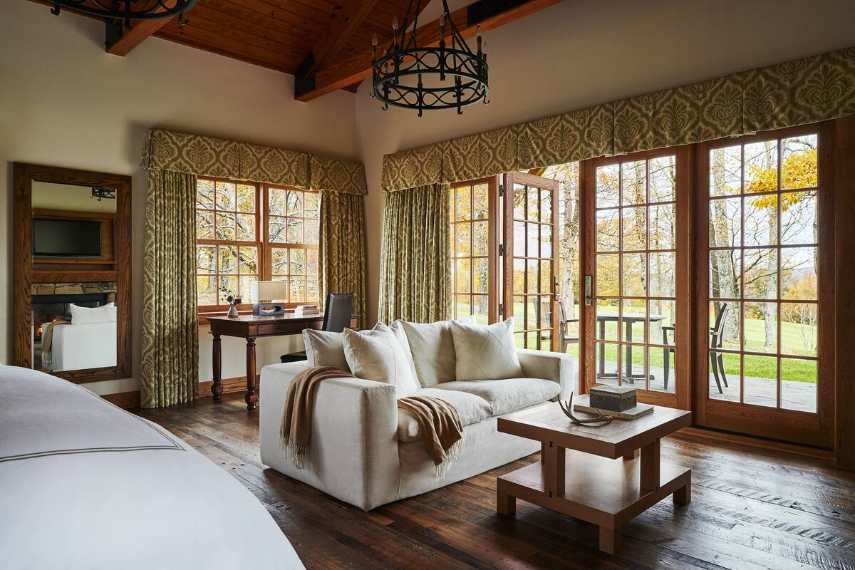 A cozy room with a sofa, a table, and large windows offering a view of the outdoors.