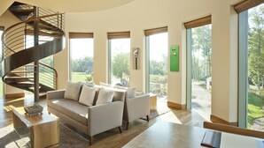 A modern living room with a spiral staircase, a sofa set, and large windows offering a view of the outdoors. - The Lodge at Primland, Auberge Collection (Meadows Of Dan)