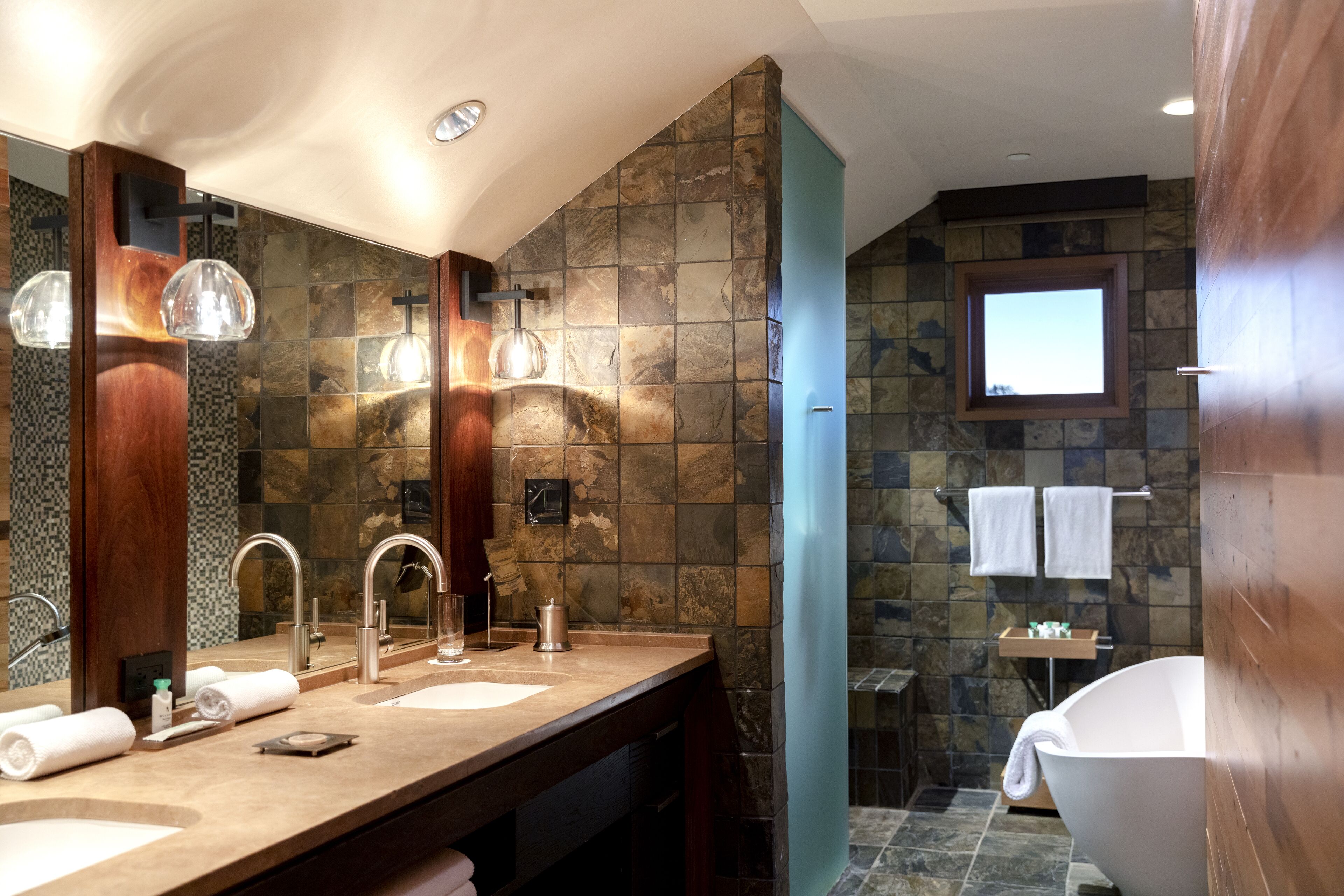 Une salle de bain moderne avec un grand miroir, deux lavabos et une baignoire.