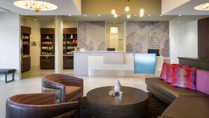 A modern lobby with a reception desk, seating area, and a large chandelier. - SpringHill Suites Philadelphia Airport Ridley Park (Ridley Park)