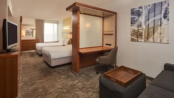 A hotel room with a bed, a desk, a TV, a chair, a sofa, and a painting on the wall.