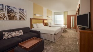 A hotel room with a sofa, a bed, a TV, and a painting on the wall. - SpringHill Suites Philadelphia Airport Ridley Park (Ridley Park)