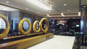 A modern hotel lobby with a marble reception desk, wooden ring-shaped decor, and seating areas. - Courtyard by Marriott Owensboro (Owensboro)