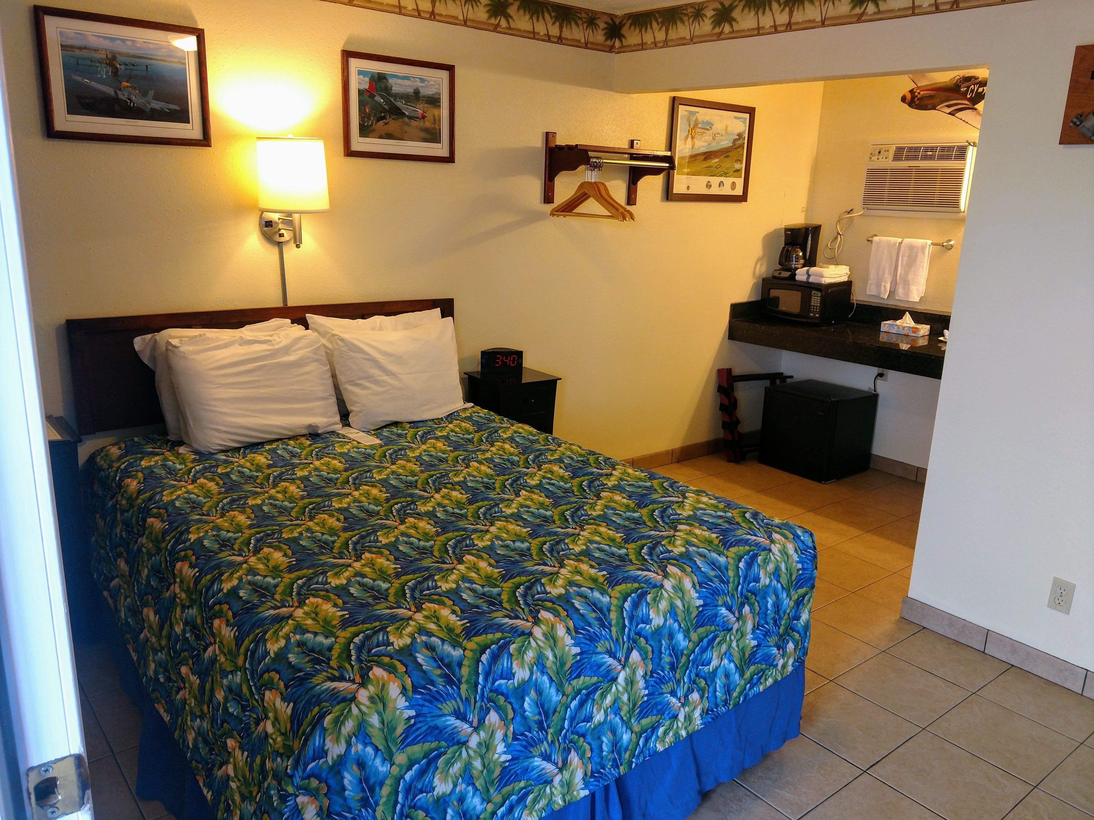 A bedroom with a bed, a nightstand, a digital clock, and a bathroom visible through an open door.
