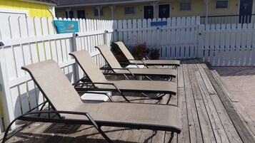 Una piscina al aire libre, sombrillas, sillones reclinables de piscina