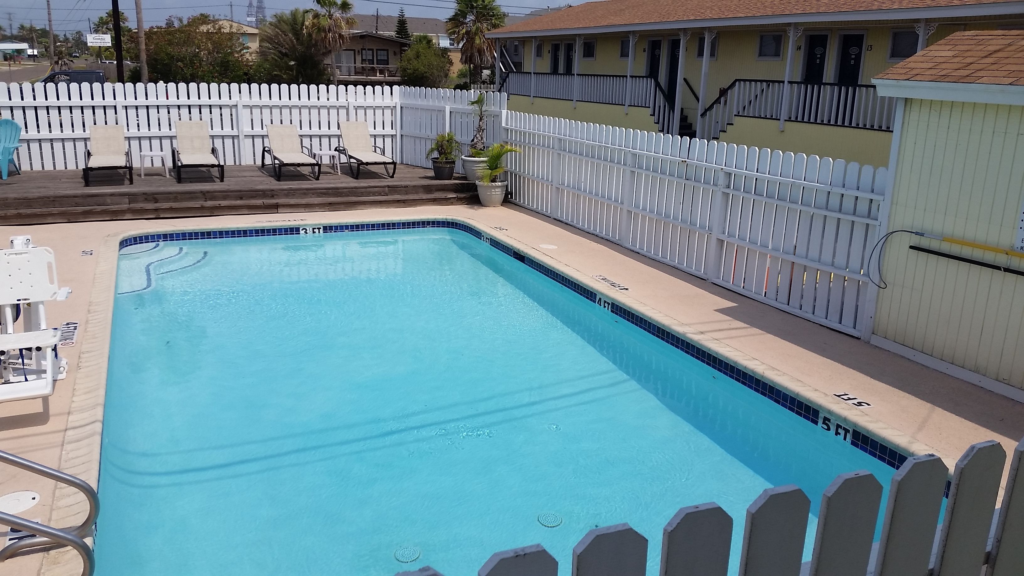 A rectangular swimming pool with a white picket fence surrounding it.