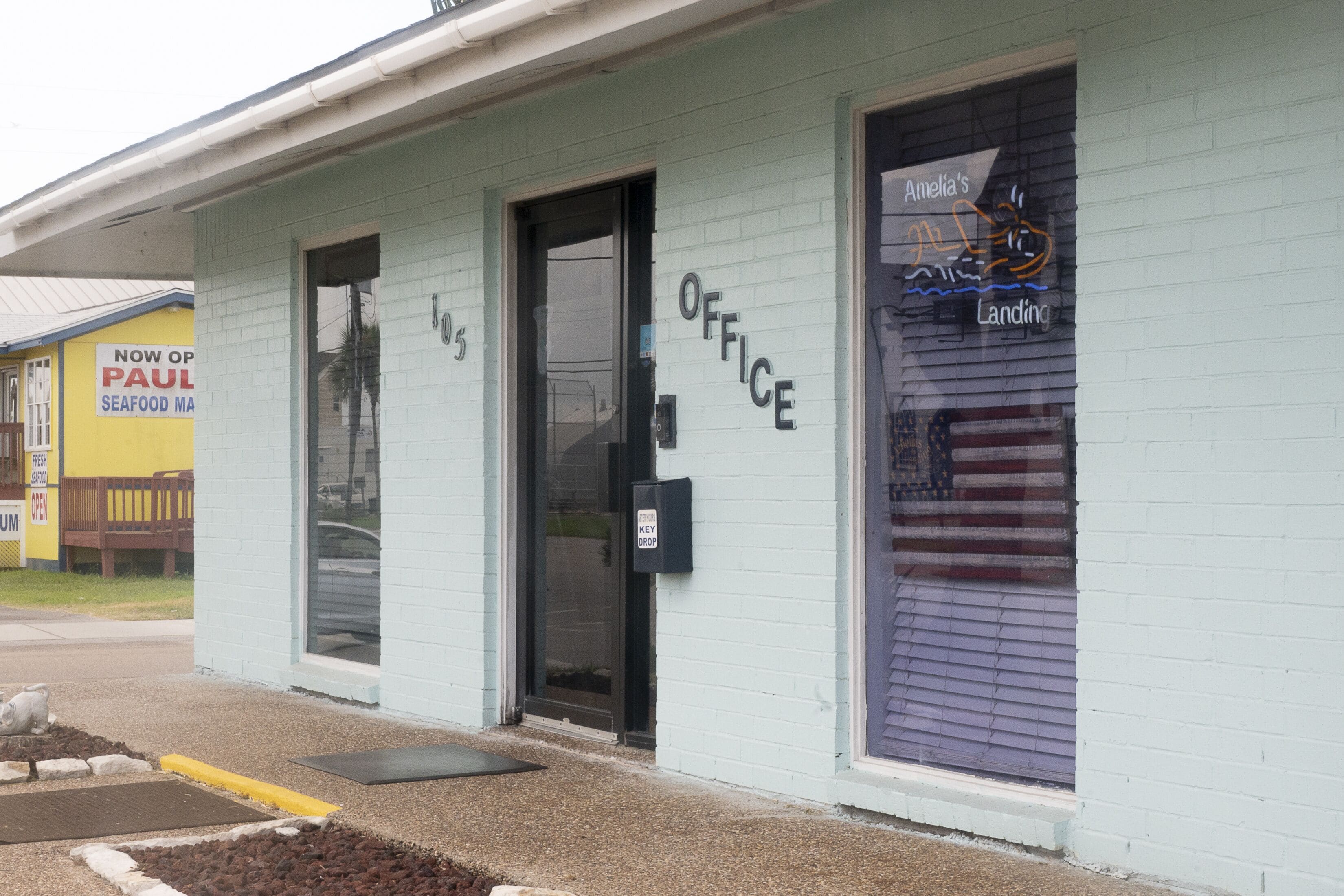 A building with a sign that reads "OFFICE" and another sign that says "Amelia's Landing."