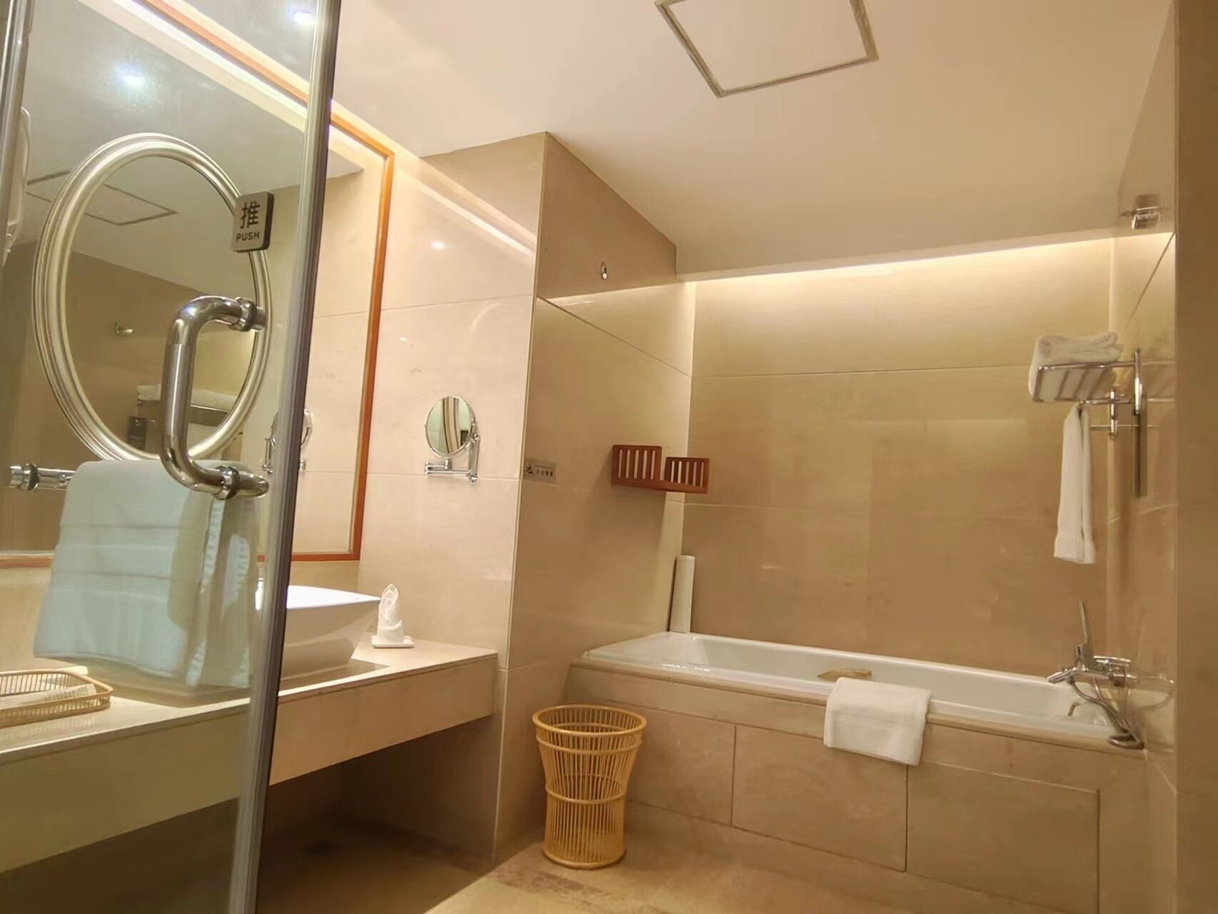 A modern bathroom with a glass-enclosed shower, a large mirror, a sink, and a bathtub.