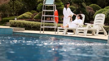 Una piscina al aire libre, sillones reclinables de piscina