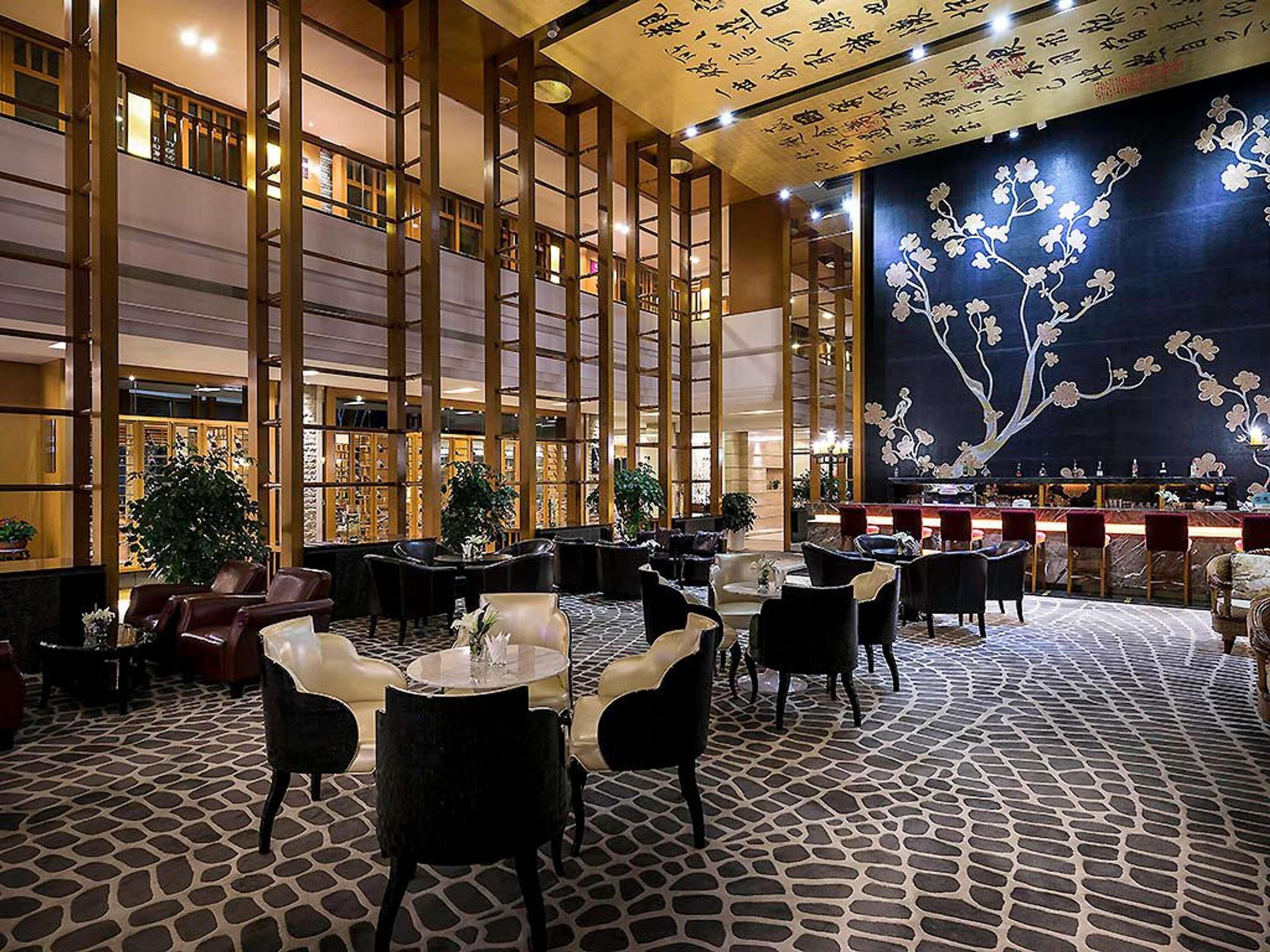 A spacious lobby with high ceilings, a central fountain, and a bar area.