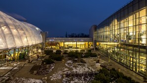 Un bâtiment moderne doté de grandes fenêtres en verre et d’une structure semblable à une serre.