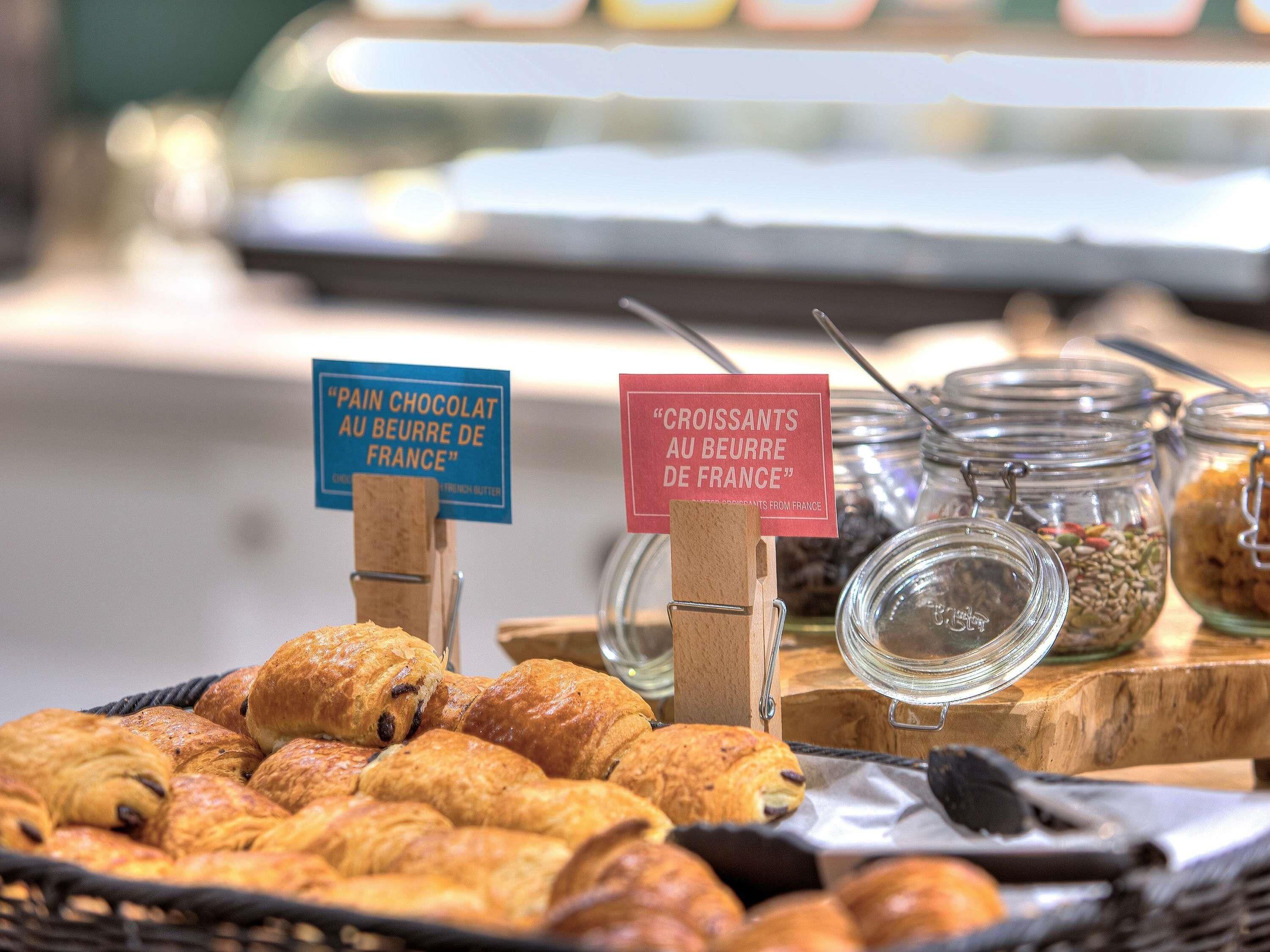Eine Auswahl an Gebäckstücken mit Schildern, die 'Pain Chocolat au Beurre de France' und 'Croissants au Beurre de France' zeigen.