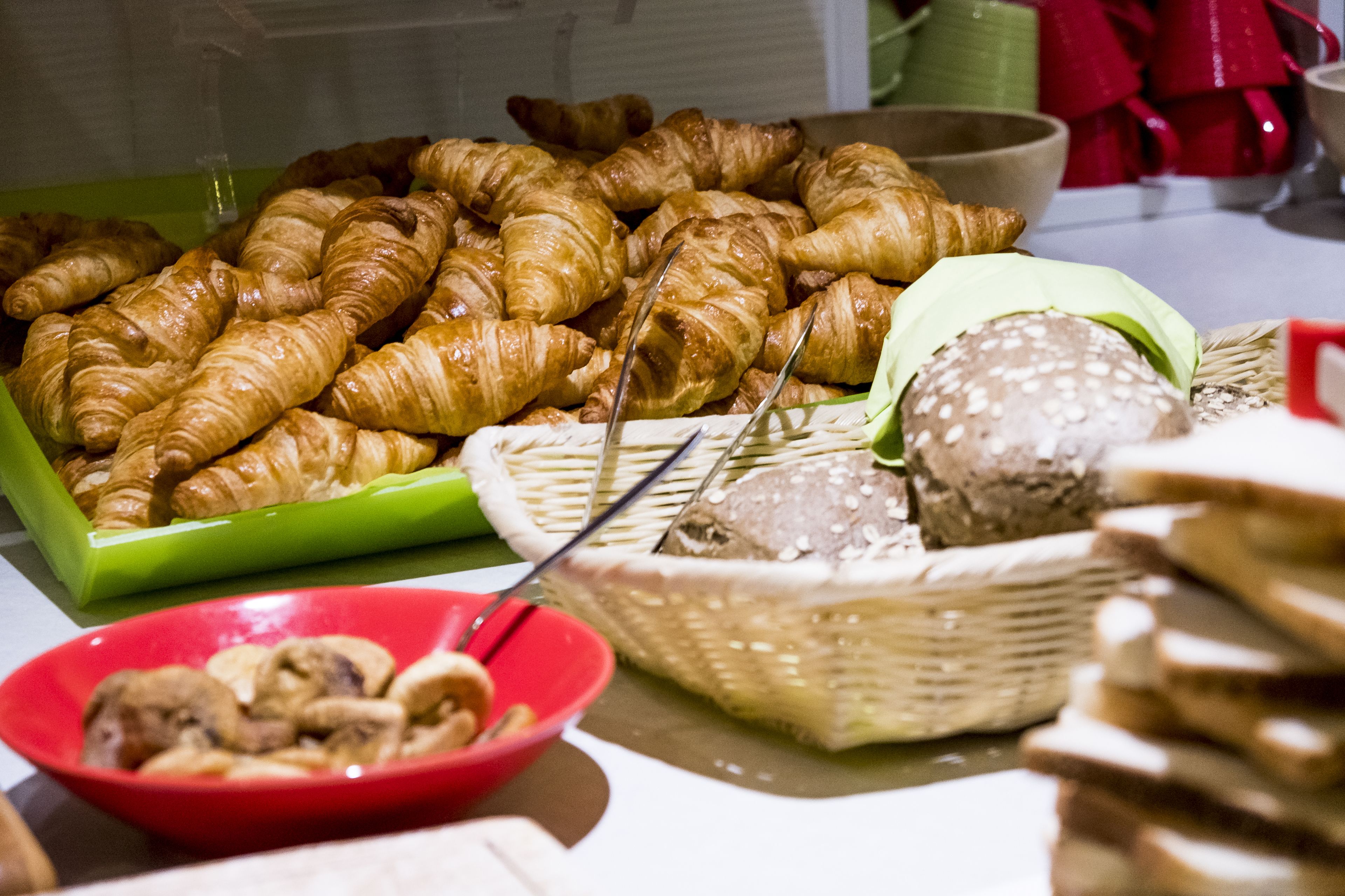 A buffet table with croissants, mushrooms, and bread.