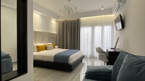 Una habitación de hotel moderna con cama, sofá, televisor y un espejo grande.
