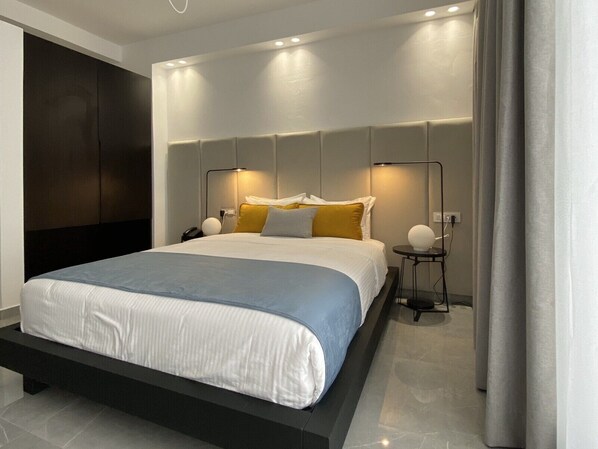 A modern hotel room with a large bed, bedside lamps, and a dark accent wall.
