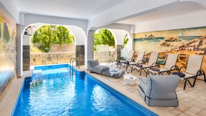 Una piscina con sillas de descanso y un mural.