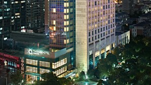 A high-rise hotel with a prominent sign at the top, multiple floors, and a well-lit facade. - The Qube Hotel (Shanghai)