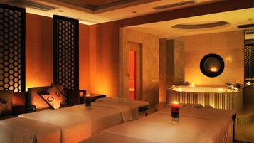 Relax in a serene space with a bathtub, two massage tables, and a decorative panel.