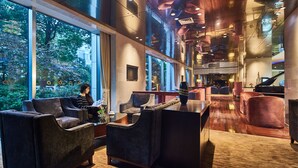 A modern lobby with large windows, plush seating, a grand piano, and a bar area. - The Qube Hotel (Shanghai)