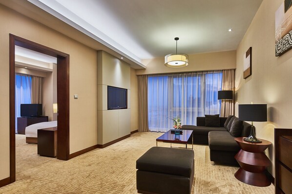 Une chambre d’hôtel avec un lit, une télévision, un canapé, une table basse et une lampe.