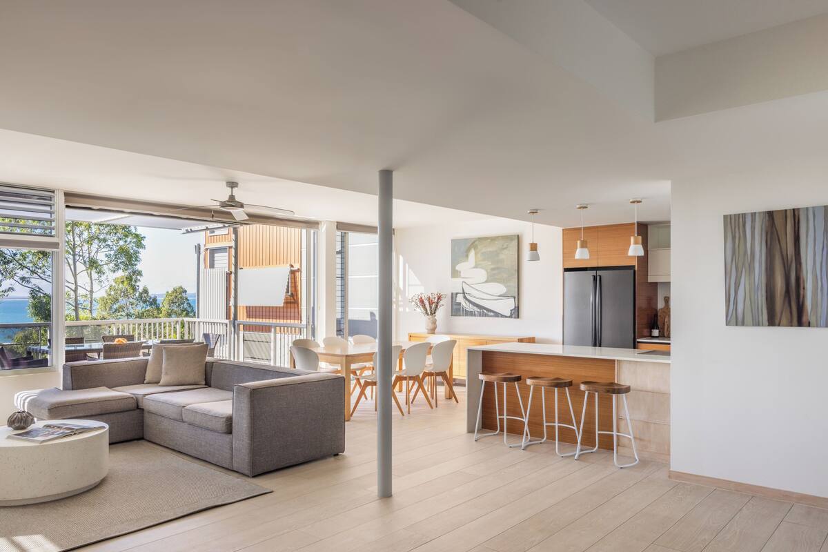 A modern living space with a dining area, kitchen, and a balcony with a view.