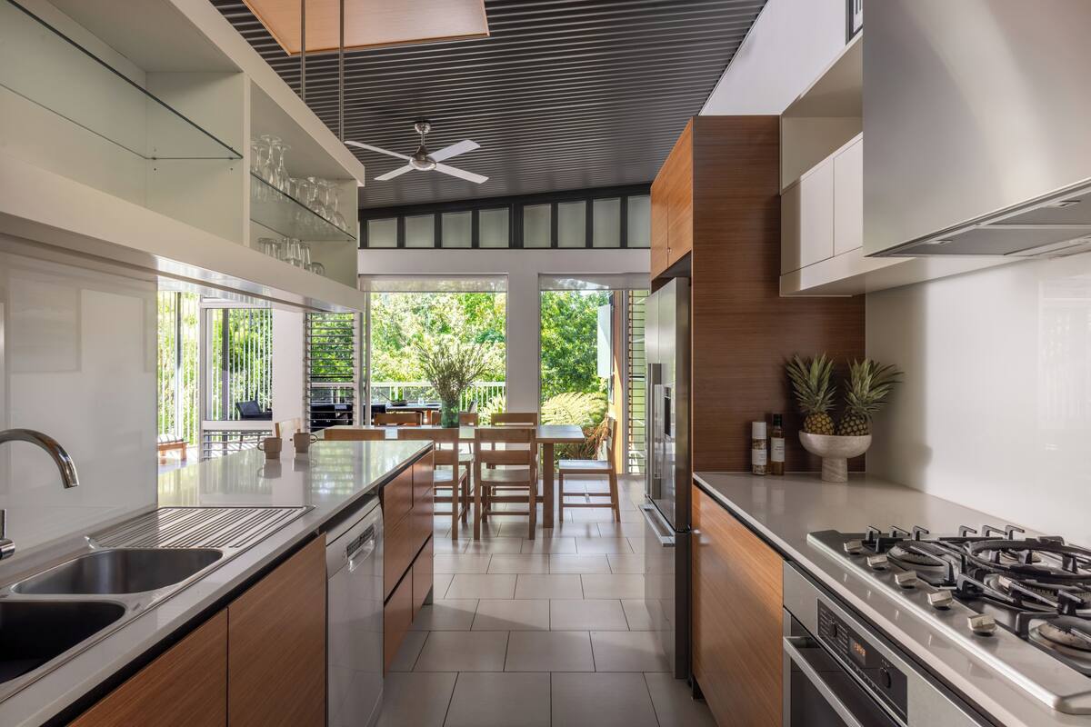 A modern kitchen with a gas stove, stainless steel appliances, and a dining area with wooden furniture.