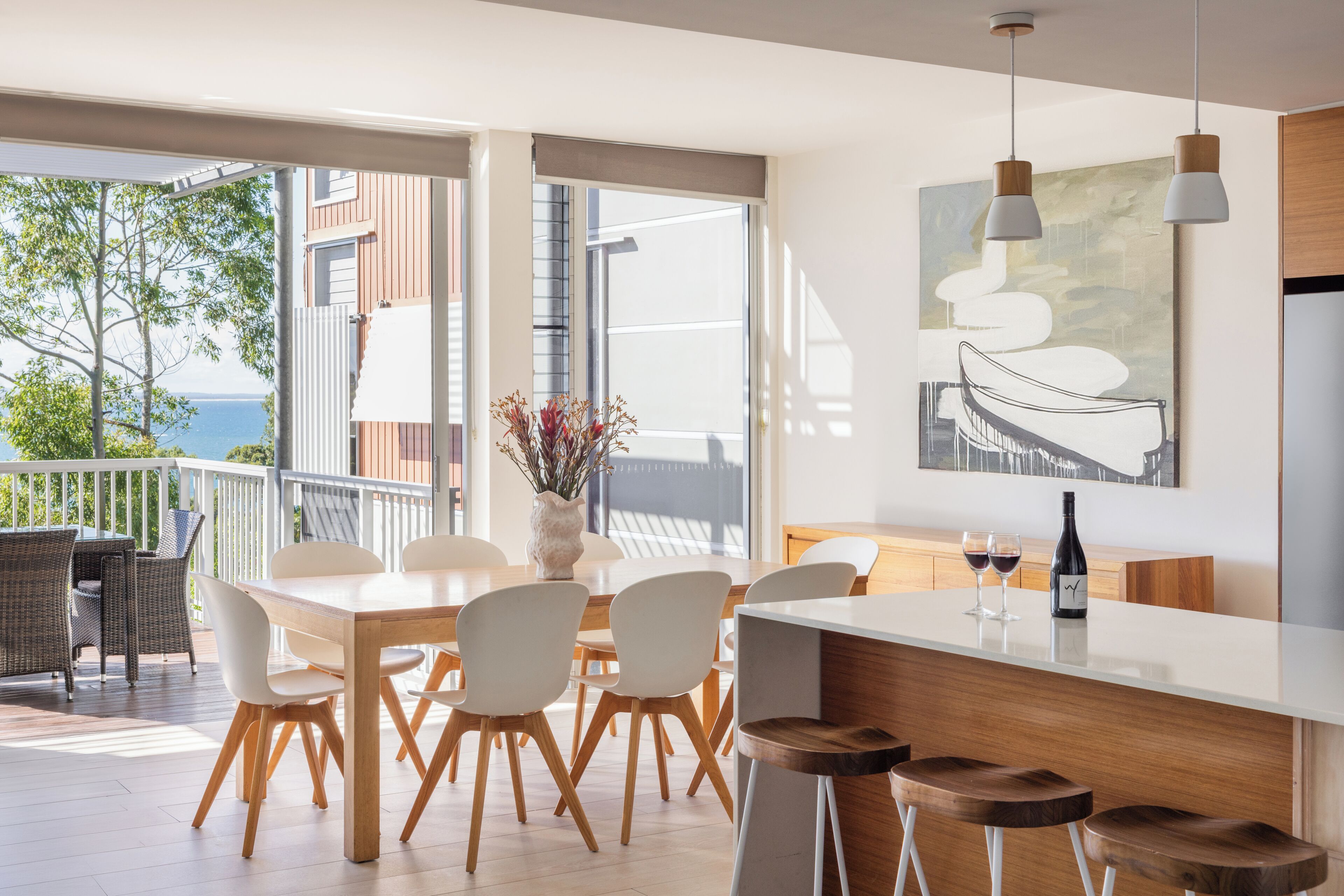 A modern kitchen with a large island, bar stools, and a dining area with chairs and a table.