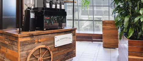 A rustic coffee station with a wooden counter, a coffee machine, and hanging plants.