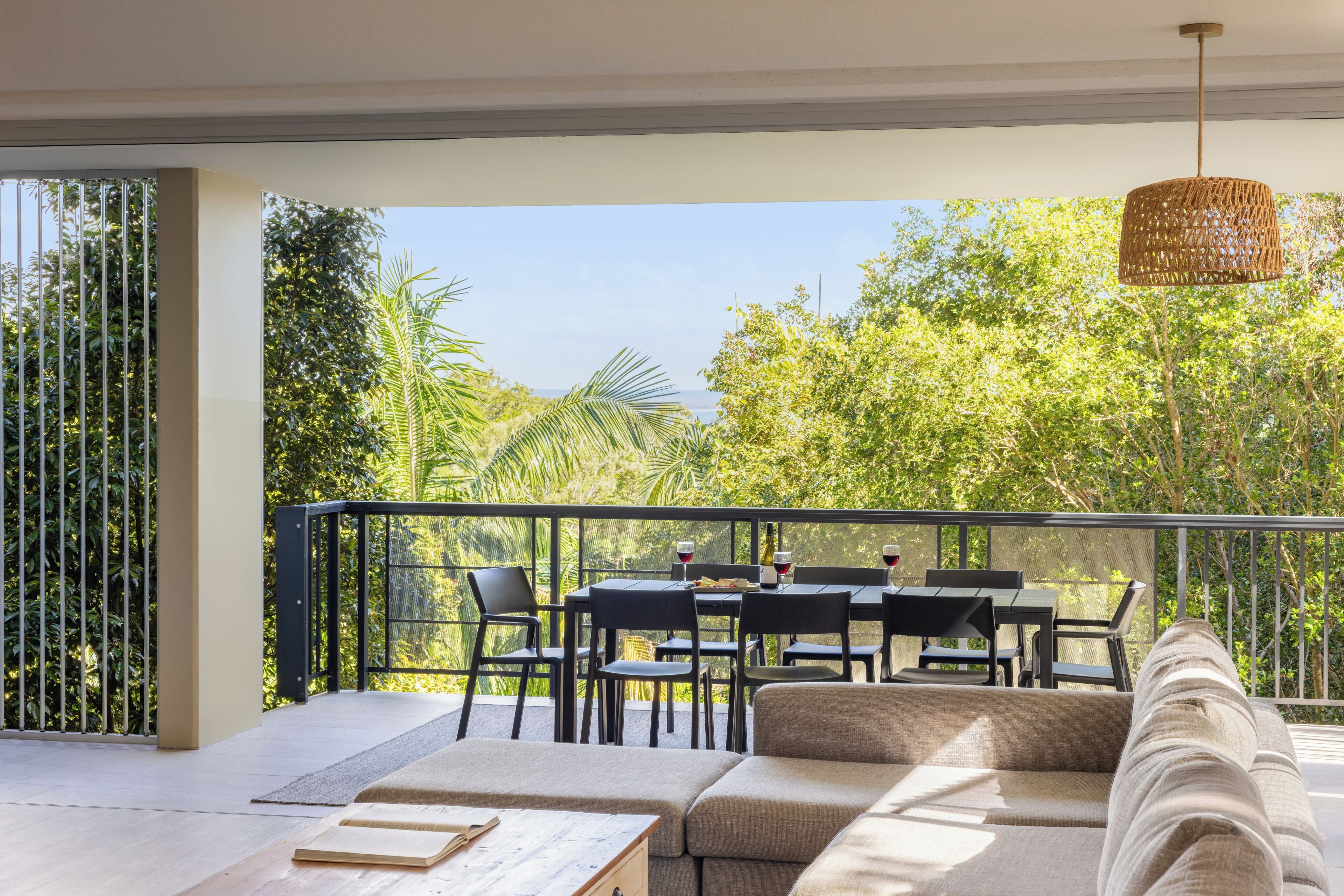 A balcony with a dining table and chairs, a sofa, and a hanging light fixture.