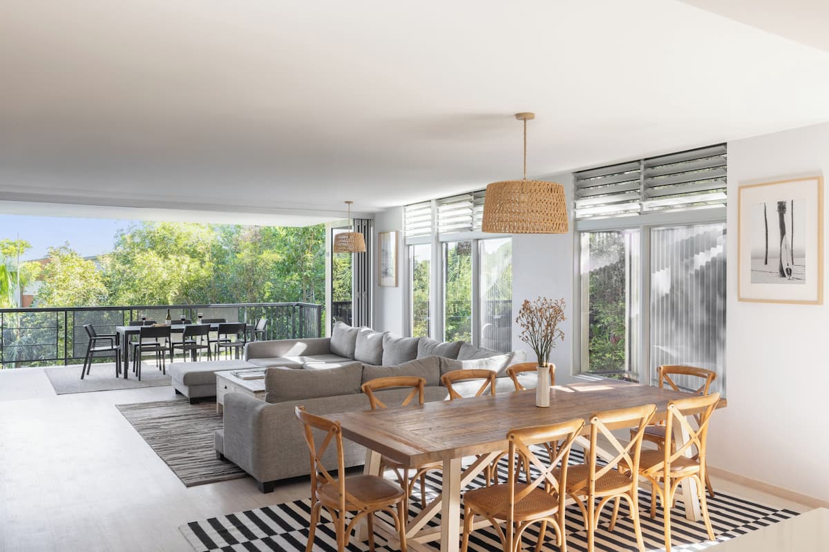 A modern living space with a dining area, sofa, and large windows.