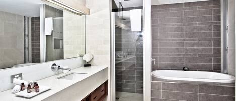 Un baño moderno con un espejo grande, un lavamanos blanco, una ducha con mampara de vidrio y una bañera.