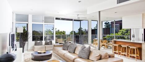 A modern living room with a beige sofa, two round coffee tables, and a large window overlooking a balcony.