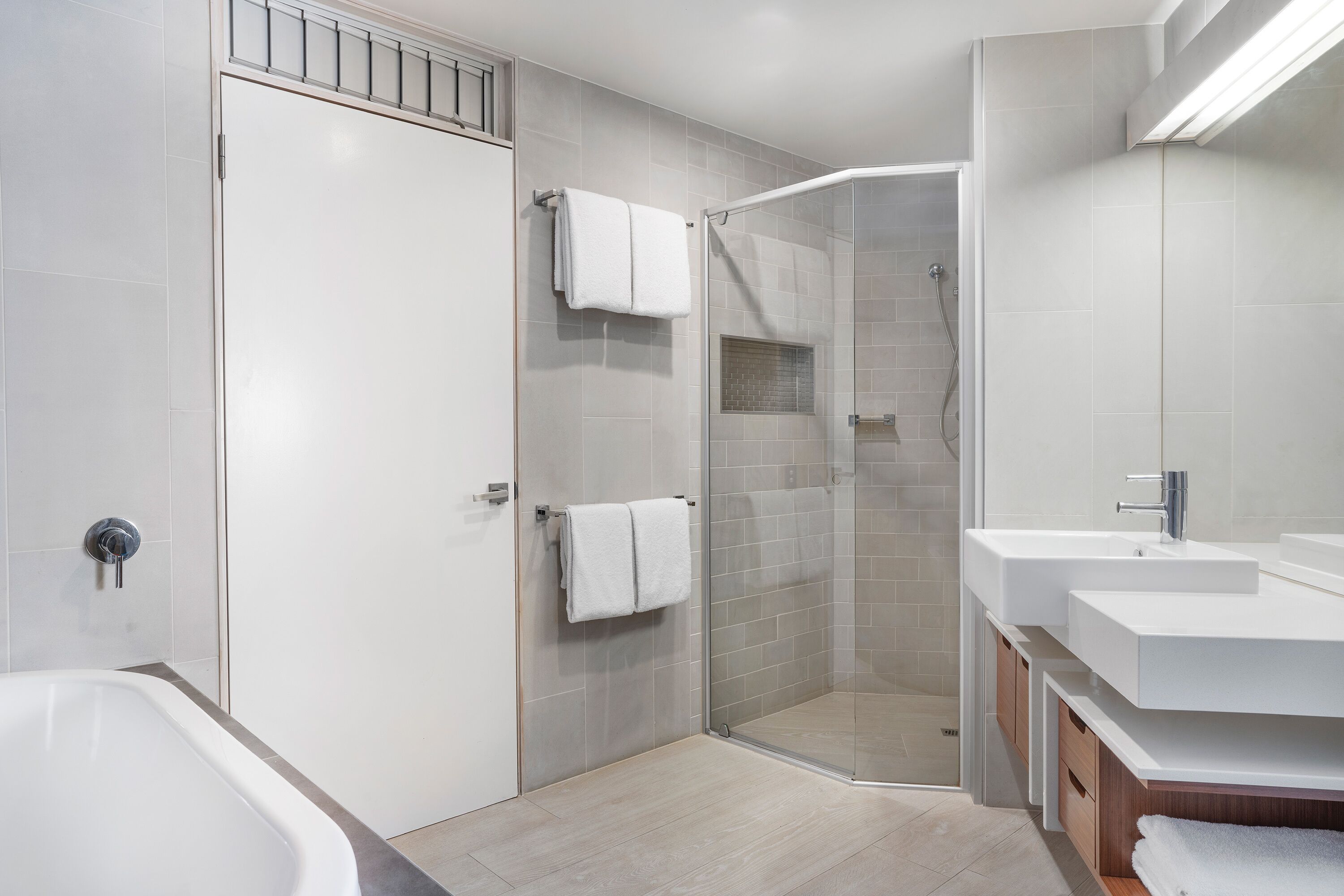 A modern bathroom with a bathtub, a glass-enclosed shower, and a vanity with a sink.