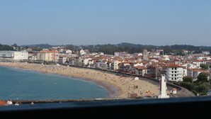 Un paysage urbain côtier avec une plage, des bâtiments et un phare.