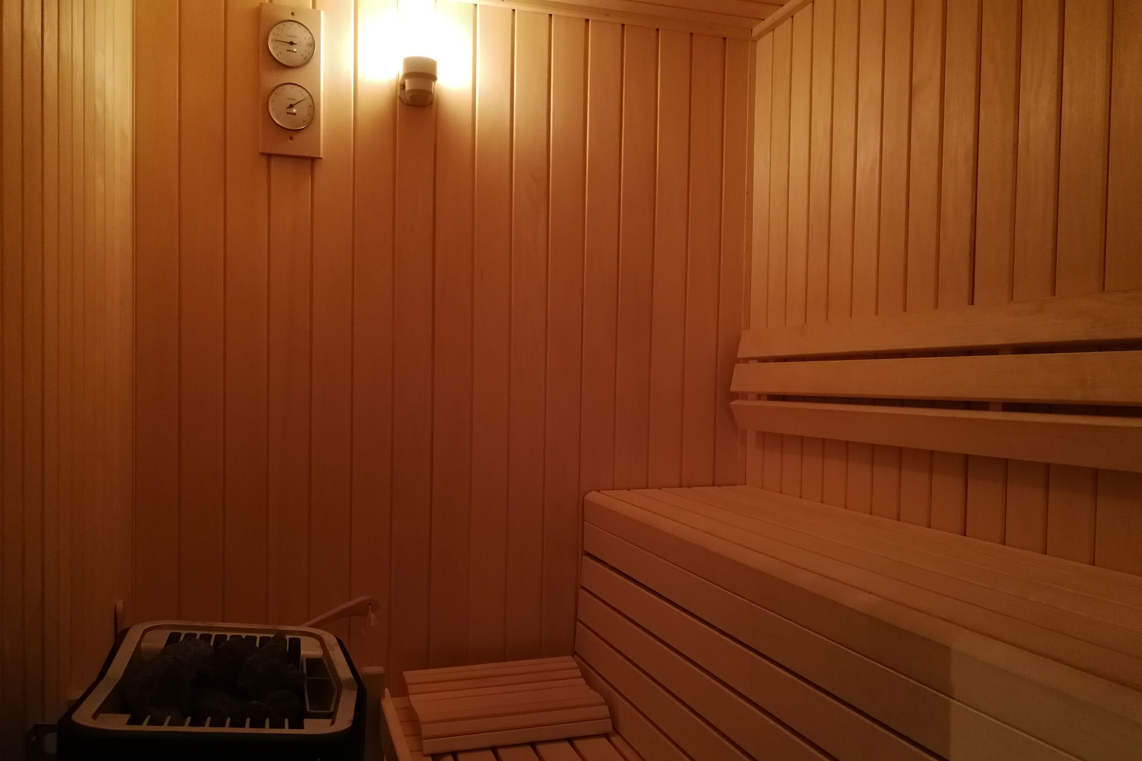 Un sauna avec des murs en bois, un banc et un appareil de chauffage.
