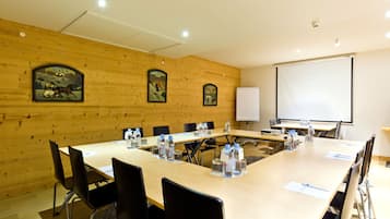 Een vergaderzaal met een lange tafel, stoelen, een projectiescherm en houten lambrisering.