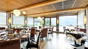 A restaurant with wooden ceiling slats, round pendant lights, and tables set for dining.