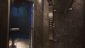 A modern shower area with a glass door, a wall-mounted showerhead, and a blue accent wall.