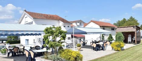 A hotel with outdoor seating, a covered patio, and a well-maintained lawn.