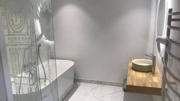 A modern bathroom with a glass-enclosed shower, a freestanding bathtub, and a wooden vanity with a sink.