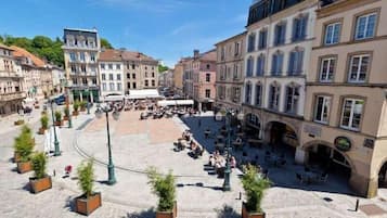 Una plaza con asientos al aire libre, rodeada de edificios históricos con arcos y una cafetería.