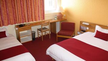 A hotel room with two beds, a desk, a chair, and a nightstand.