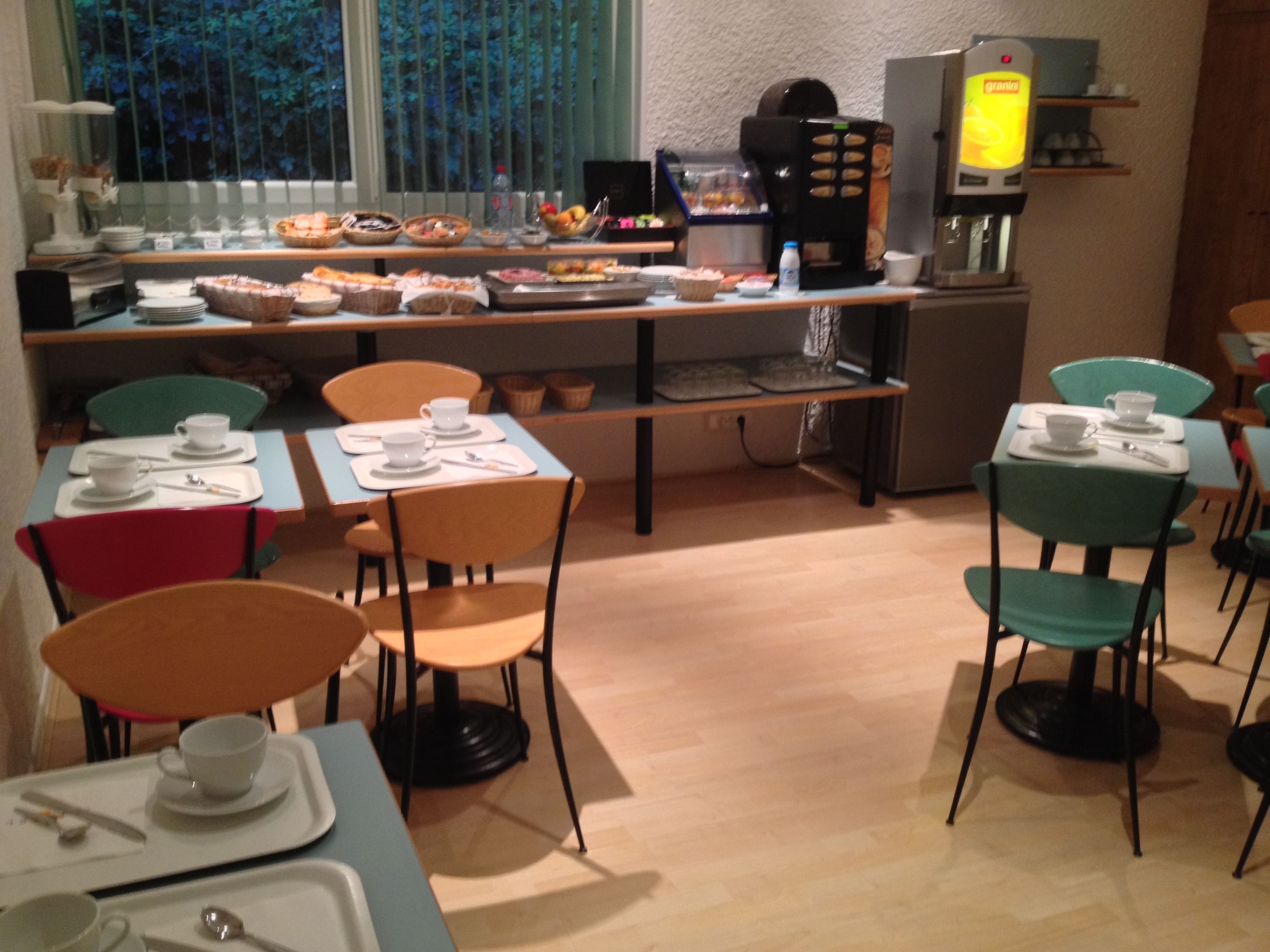 Een ontbijtruimte met tafels, stoelen en een koffieapparaat.